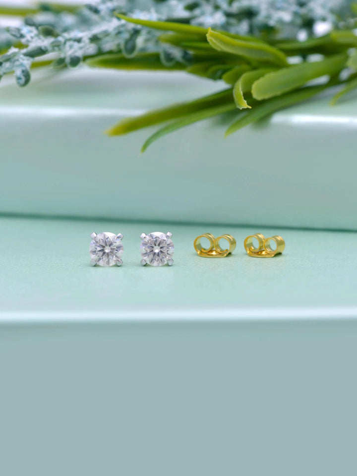 14K Solid Gold 5mm Moissanite Stud Earrings by Carat For You on creative background with green leaves.