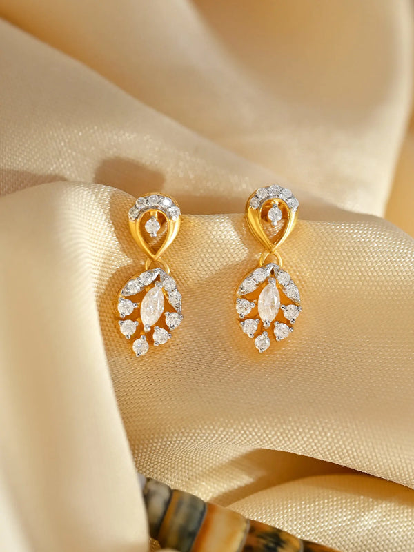 A pair of dangle drop earrings with round and marquise shaped moissanite stones set in 925 sterling silver, displayed against a silky beige fabric background.