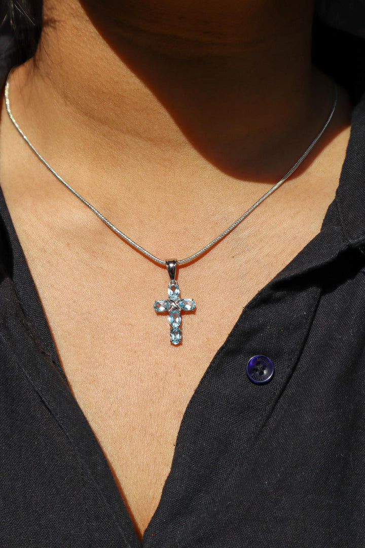 A closeup image of a girl wearing Celestial Cross Blue Topaz Pendant -2 by carat For You