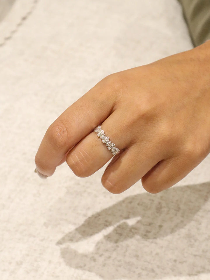 Close-up of a hand wearing a diamond ring on a neutral background