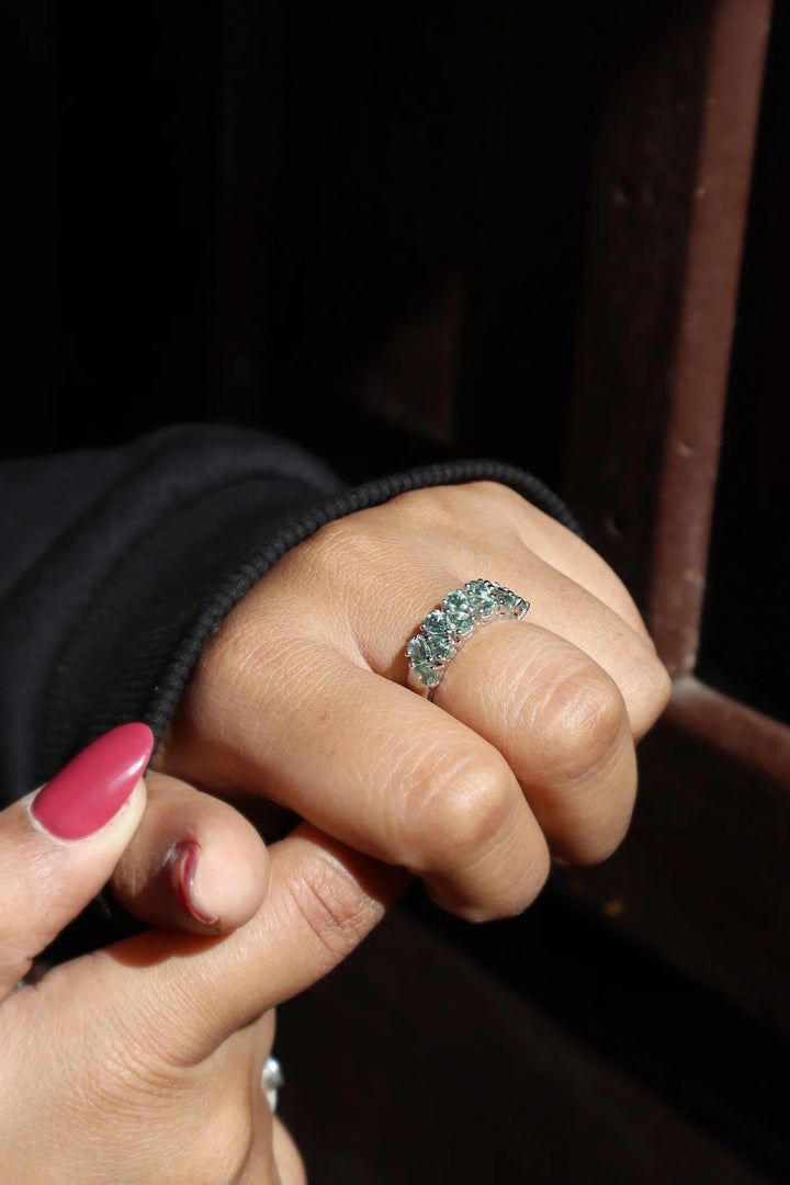 Hand in black sweater wearing Natural Green Sapphire Band Ring by Carat For You