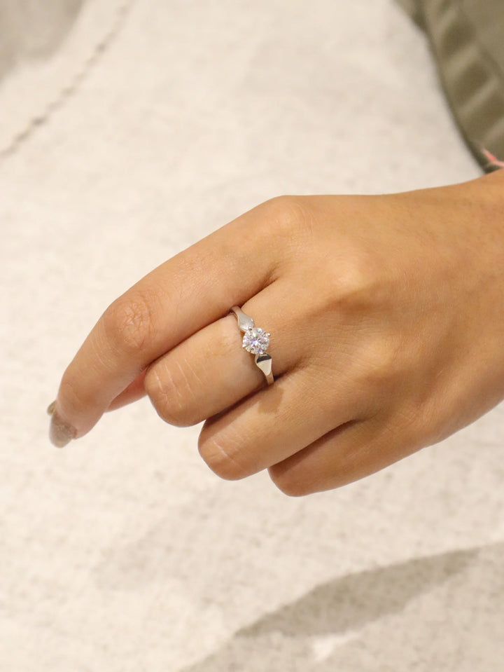 Hand wearing a diamond ring on a neutral background