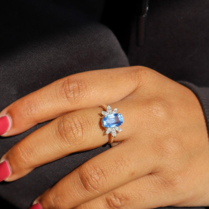 A model's hand displaying a sky blue kyanite gemstone ring with rhodium plating on a 925 Sterling Silver Band by Carat For You