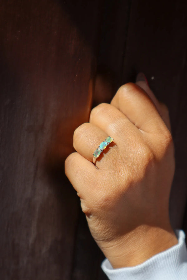 Hand wearing a ring with a visible Oval gemstone against a dark background
