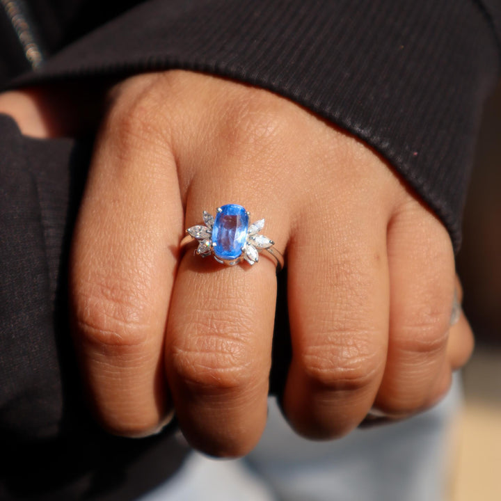 A model's hand displaying a sky blue kyanite gemstone ring with rhodium plating on a 925 Sterling Silver Band by Carat For You