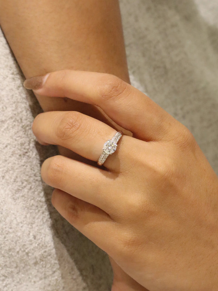 Hand wearing a diamond ring on a neutral background