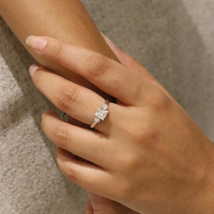 Close-up of a hand wearing a diamond ring on a neutral background