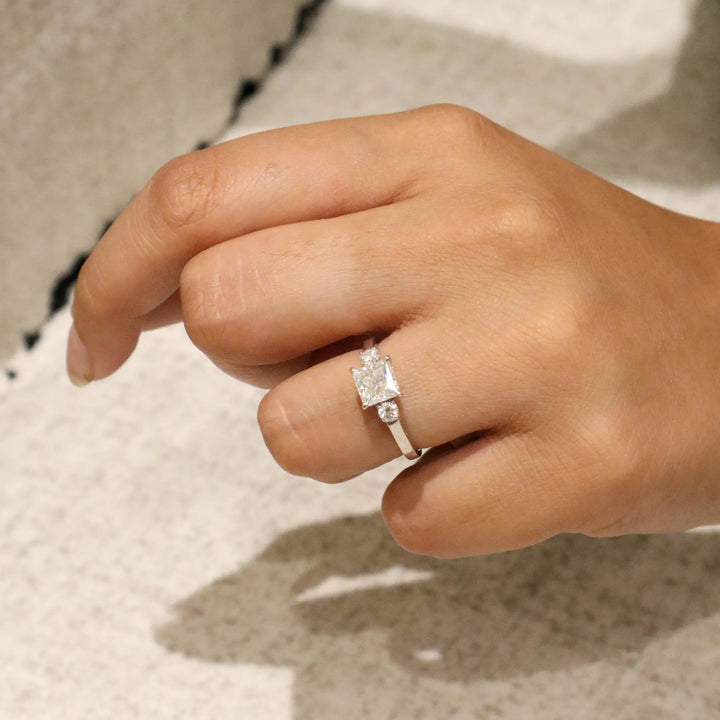 Hand wearing a diamond ring on a neutral background